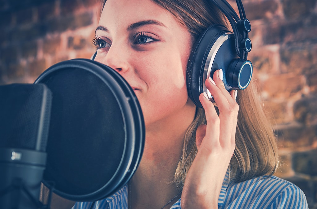 enregistrement vocal en studio devant un micro et casque d'écoute